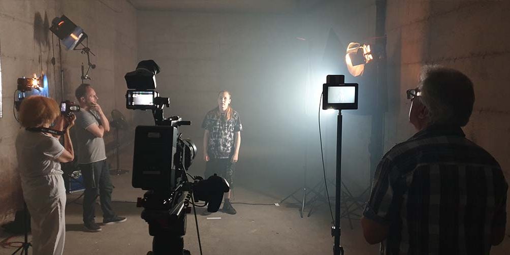 Filmteam mit Kameras und Protagonist im Innenraum mit Filmlicht