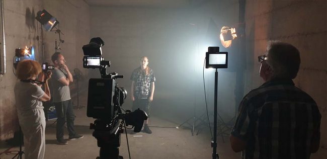 Filmteam mit Kameras und Protagonist im Innenraum mit Filmlicht