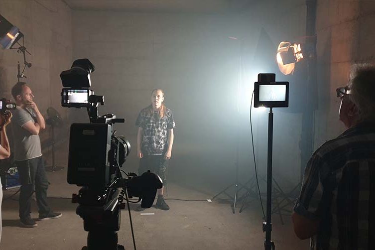 Filmteam mit Kameras und Protagonist im Innenraum mit Filmlicht